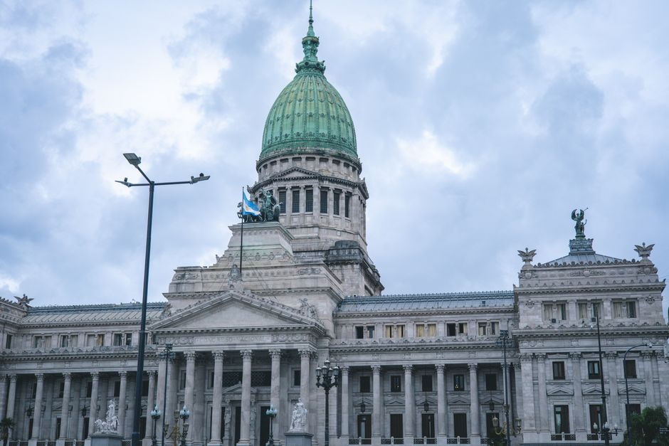 Política Nacional — Upward view of the iconic National Congress building in Buenos Aires with cloudy sky.