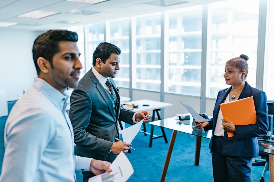 Política Nacional — Business professionals discussing documents in a modern office environment.